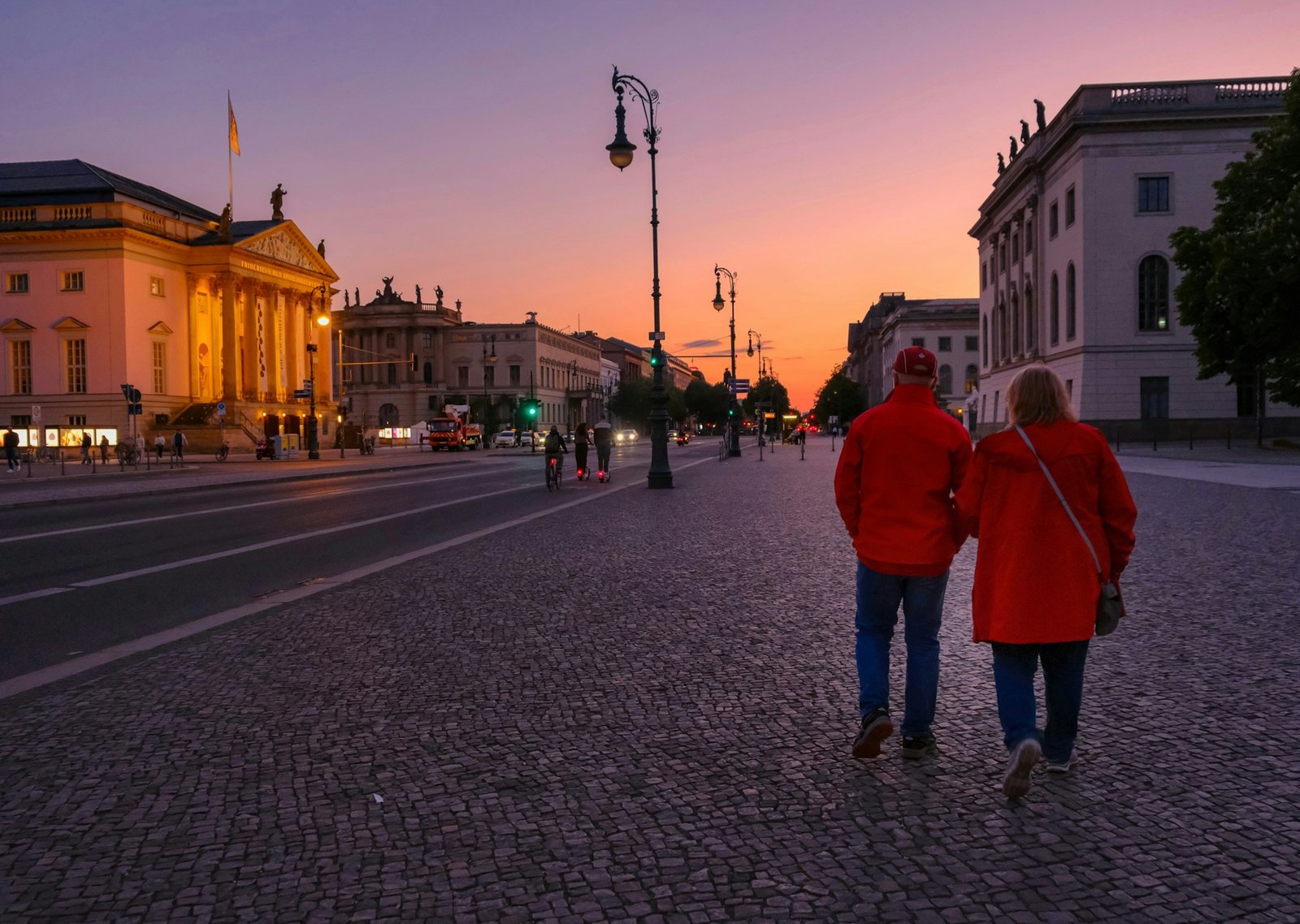 Two people walking down a street at sunset
