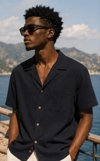 Man in navy camp collar shirt overlooking the sea