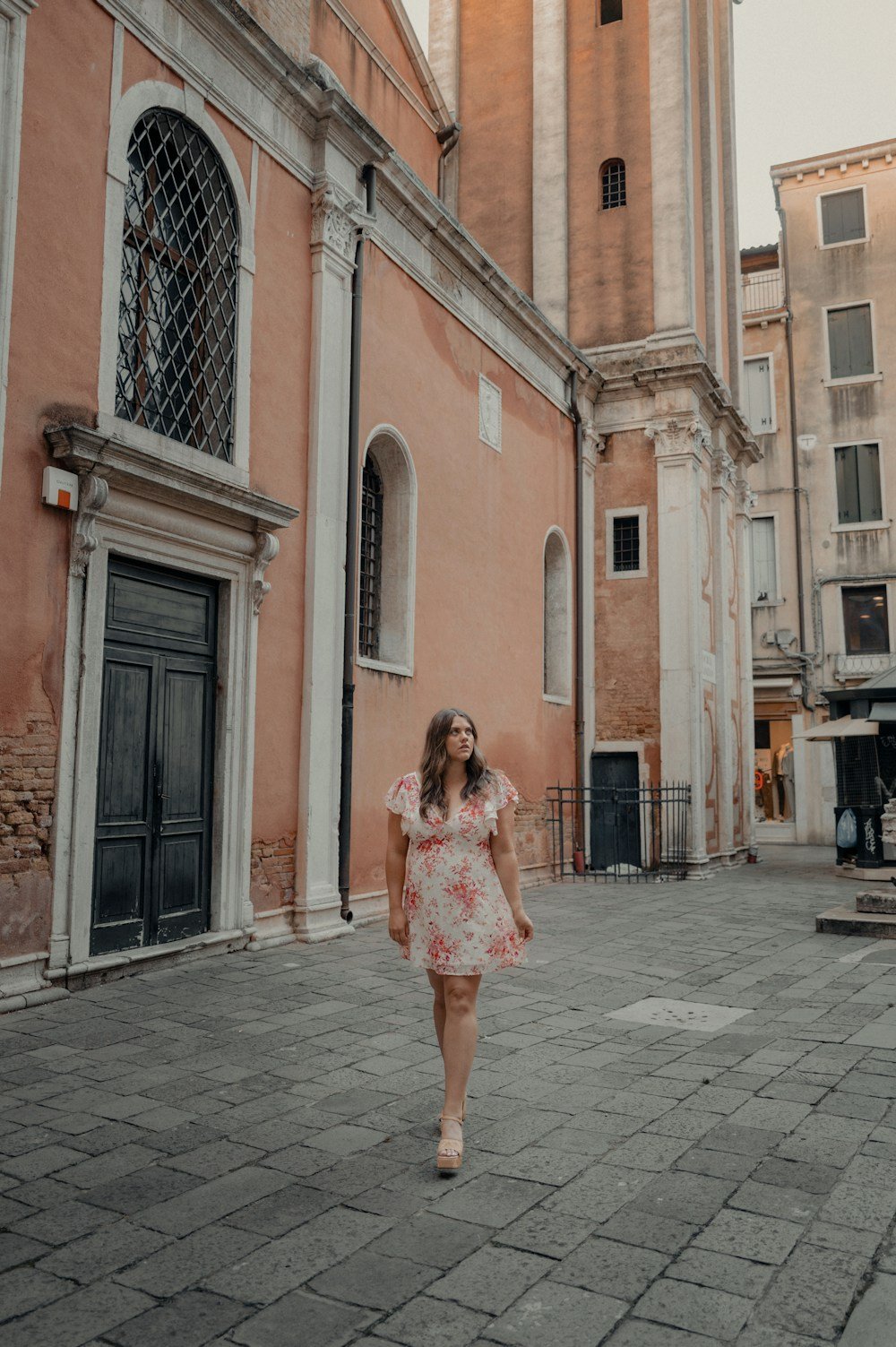Woman in floral dress walking on a cobblestone street